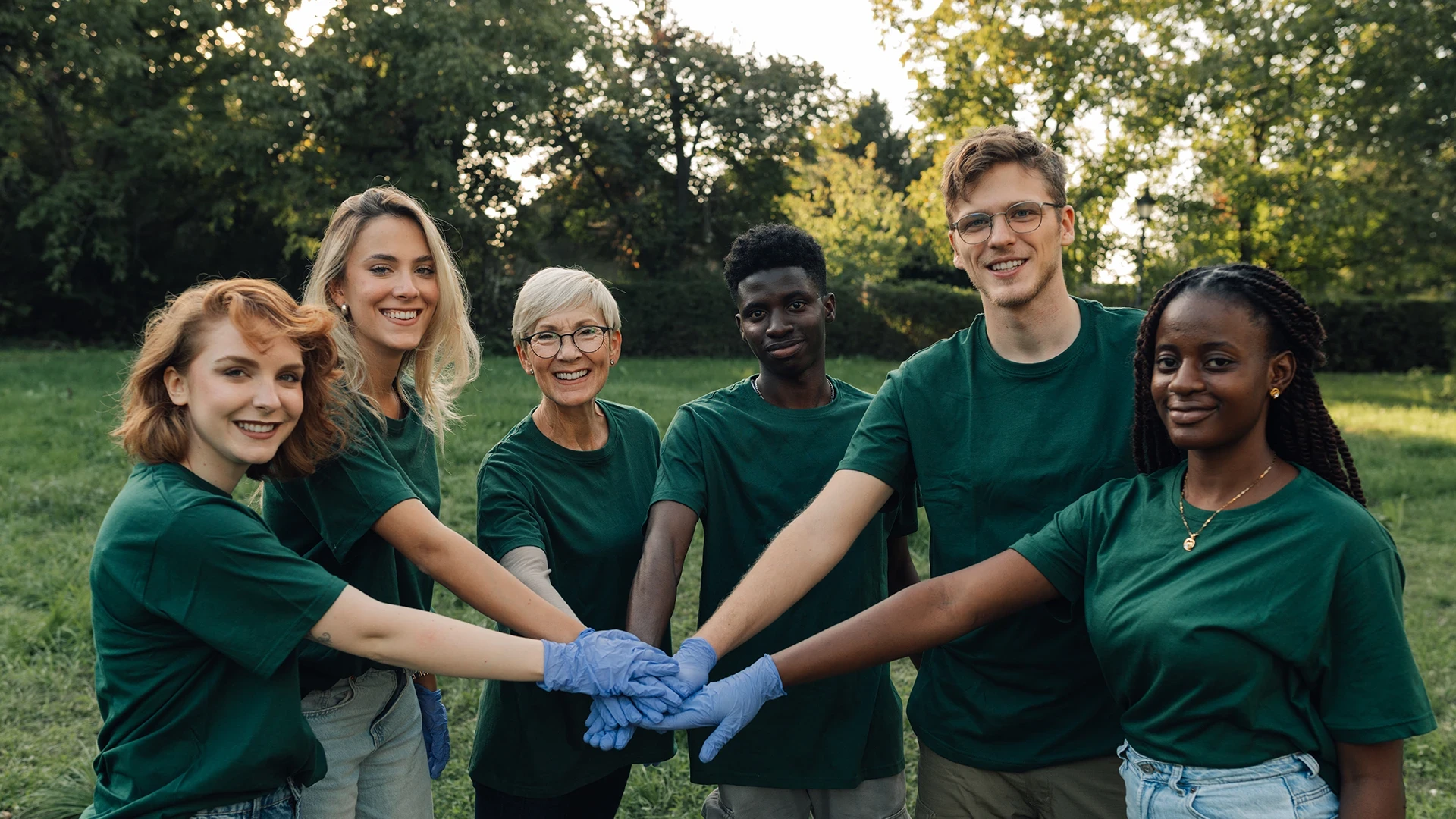 group-of-volunteers-putting-hands-together-wearing-green-shirt